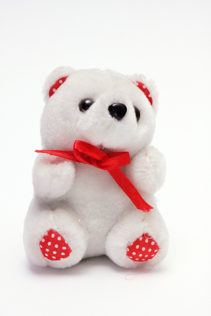 White stuffed teddy with a red bow.